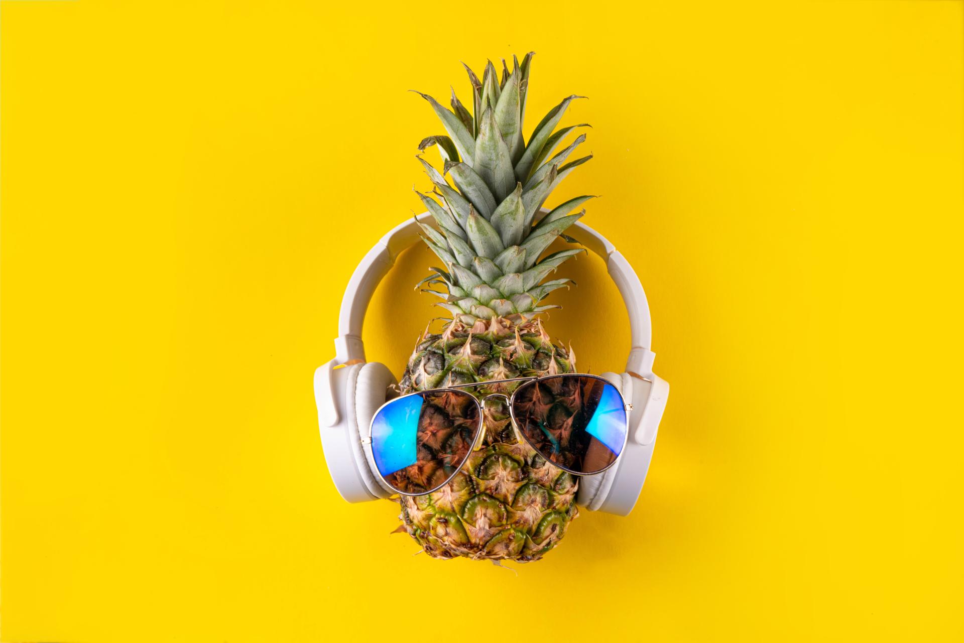 pineapple wearing sunglasses and headphones over a yellow background pineapple wearing sunglasses and headphones over a yellow background