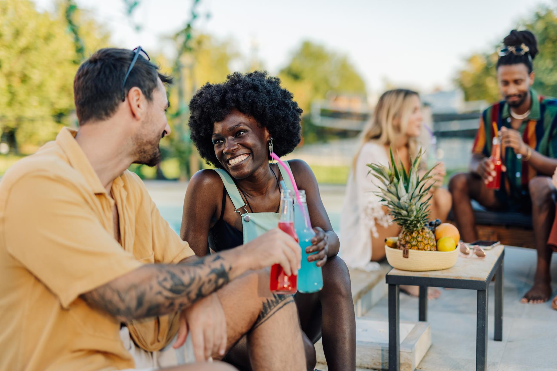 happy flirtatious people sipping bottled drinks poolside around a platter of fresh fruit happy flirtatious people sipping bottled drinks poolside around a platter of fresh fruit