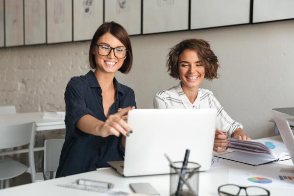 Two smiling successful businesswomen and SDC Partners working together on a laptop Two smiling successful businesswomen and SDC Partners working together on a laptop