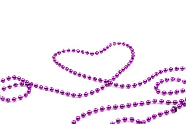 Purple party beads forming a heart shape Purple party beads forming a heart shape