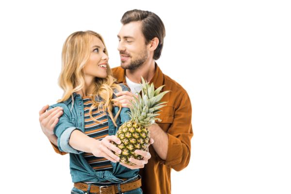white swinger couple looking adoringly at each other while holding a pineapple white swinger couple looking adoringly at each other while holding a pineapple