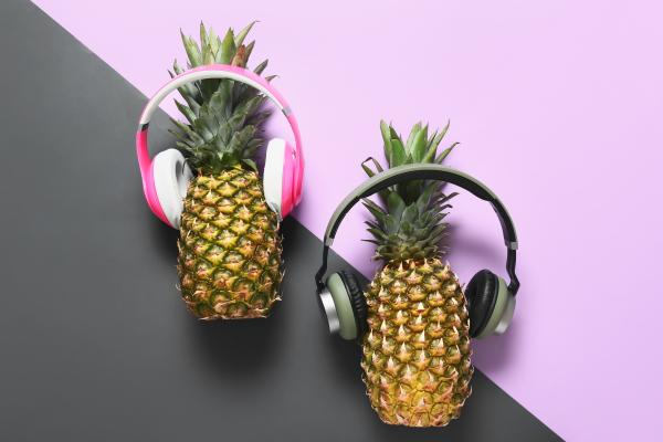 A pair of pineapples on a black and light purple background wearing headphones A pair of pineapples on a black and light purple background wearing headphones