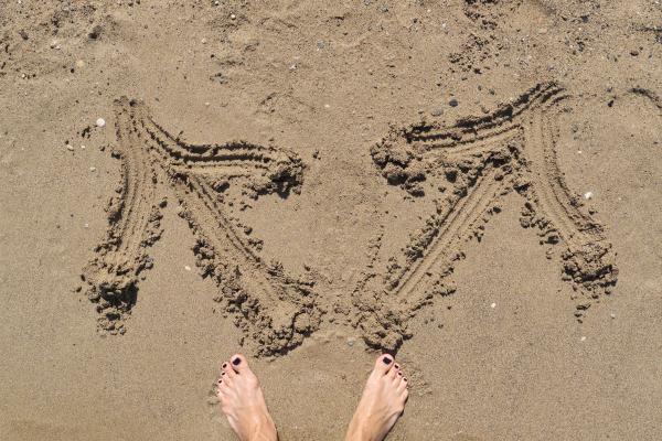 Photo of a person standing on a beach with two opposing arrows drawn in the sand Photo of a person standing on a beach with two opposing arrows drawn in the sand