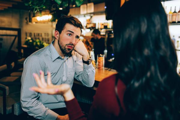 A photo of a man looking perplexed and defeated as a woman gestures before him in confusion A photo of a man looking perplexed and defeated as a woman gestures before him in confusion