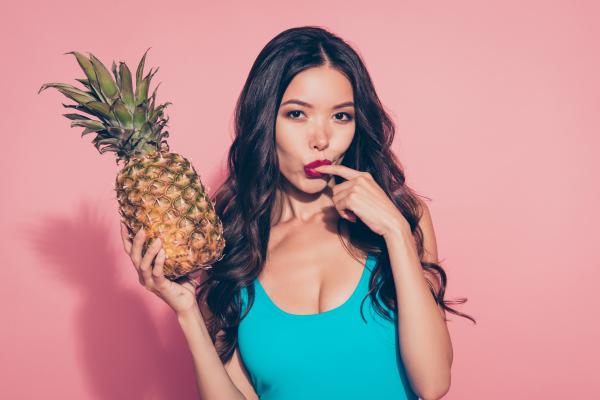 A photo of a woman sucking her finger seductively while holding a pineapple A photo of a woman sucking her finger seductively while holding a pineapple