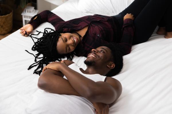 a photo of a happy Black couple fully clothed on a bed having a conversation a photo of a happy Black couple fully clothed on a bed having a conversation