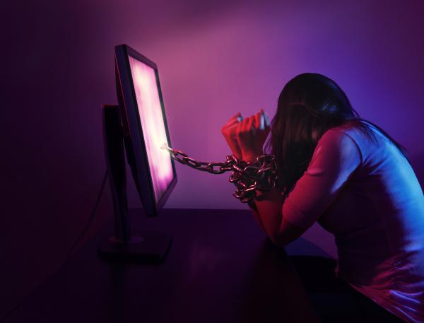 a photo of a woman turning away from her computer with chains on her wrists coming from the screen a photo of a woman turning away from her computer with chains on her wrists coming from the screen