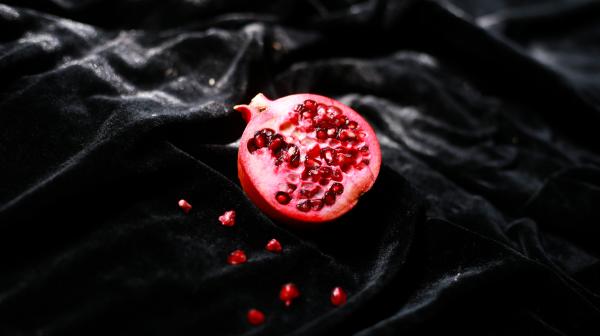 a photo of a sliced pomegranate on a black cloth background a photo of a sliced pomegranate on a black cloth background