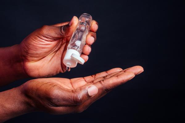 a photo of a Black man's hands about to dispense silicone lubricant from a small clear bottle a photo of a Black man's hands about to dispense silicone lubricant from a small clear bottle