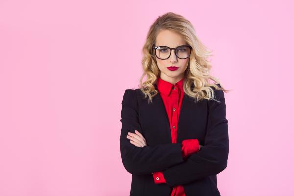 woman in a black blazer and red blouse looking incredulous over pink background woman in a black blazer and red blouse looking incredulous over pink background