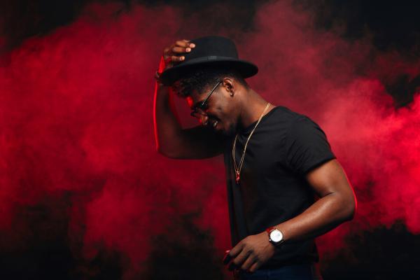 an attractive Black man wearing all black and a hat dancing over a smoky red background an attractive Black man wearing all black and a hat dancing over a smoky red background