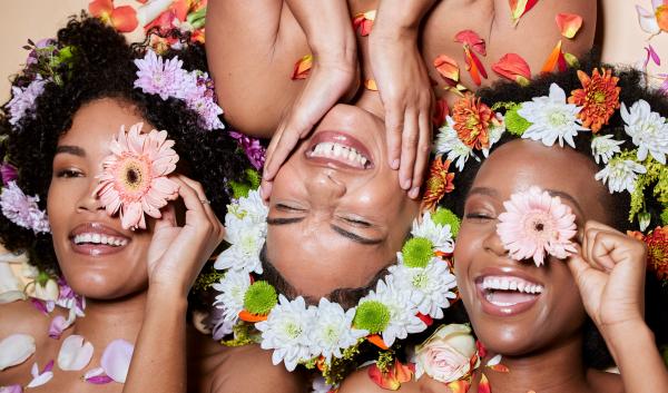 three smiling Black women covered in colorful flowers and petals three smiling Black women covered in colorful flowers and petals