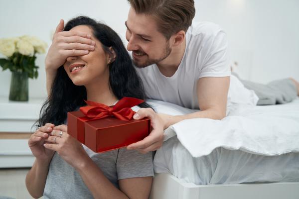 man giving a woman a gift in bed man giving a woman a gift in bed