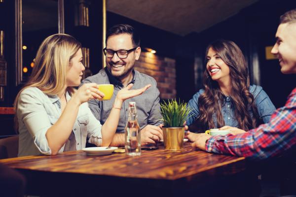 two couples talking while having coffee at a wooden table two couples talking while having coffee at a wooden table