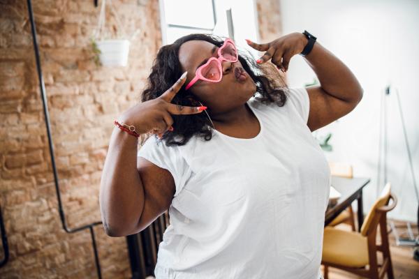curvy Black woman wearing pink heart sunglasses and making peace signs curvy Black woman wearing pink heart sunglasses and making peace signs
