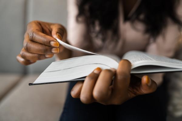 Black woman holding a bible in her lap and flipping a page Black woman holding a bible in her lap and flipping a page