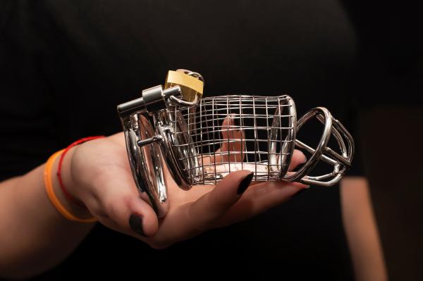 closeup of a woman's hand holding a penile cage for BDSM dynamics closeup of a woman's hand holding a penile cage for BDSM dynamics