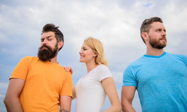 a woman smiling at one man and standing next to another man who is looking away a woman smiling at one man and standing next to another man who is looking away