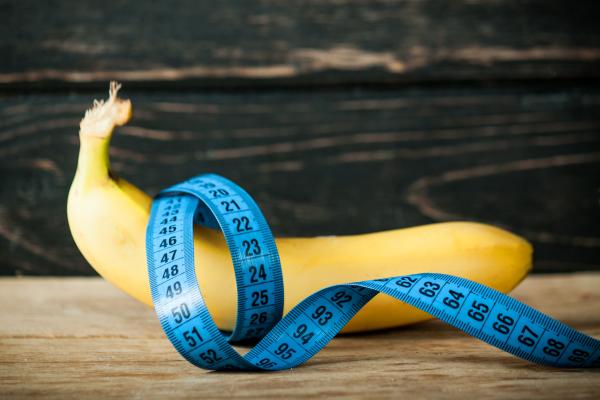 banana next to blue centimeters measuring tape on a wooden backdrop banana next to blue centimeters measuring tape on a wooden backdrop