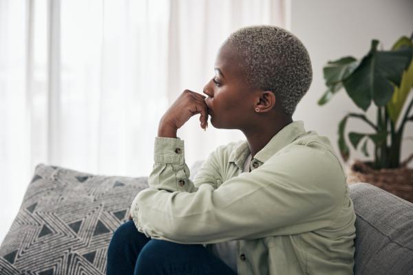 woman curled up on a couch lost in deep contemplation woman curled up on a couch lost in deep contemplation