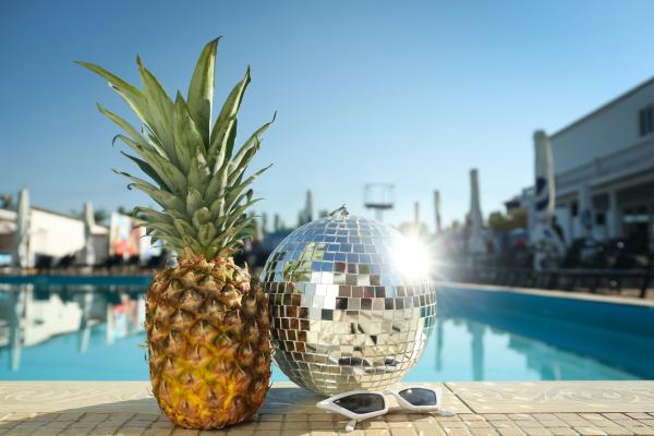 Daytime hotel poolside pineapple and disco ball reflecting the sun Daytime hotel poolside pineapple and disco ball reflecting the sun