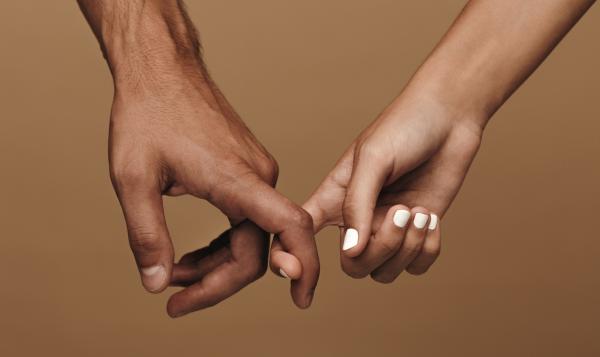 Closeup of two hands loosely hooking index fingers over a brown background Closeup of two hands loosely hooking index fingers over a brown background