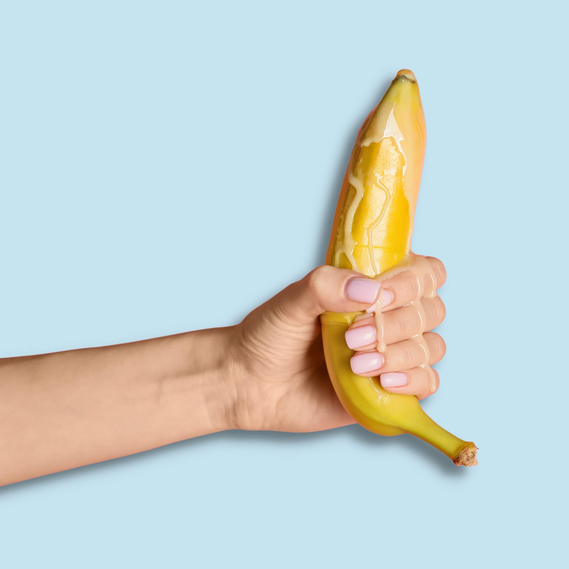a photo of a woman's hand holding a banana dripping liquid from the end