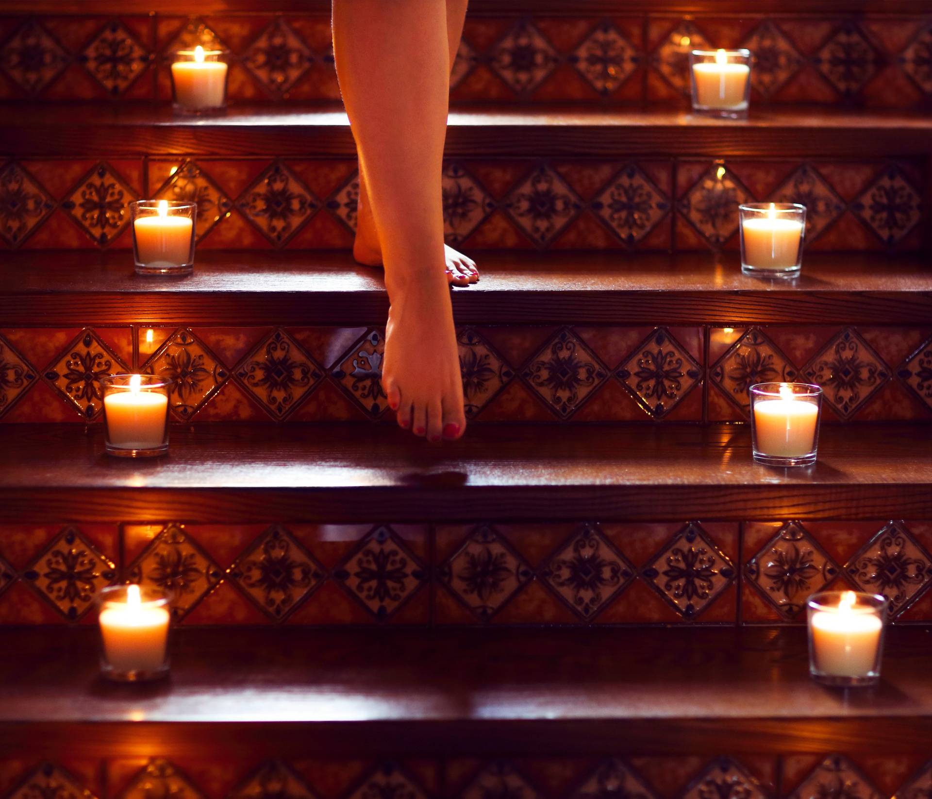 woman walking up stairs lined with candles