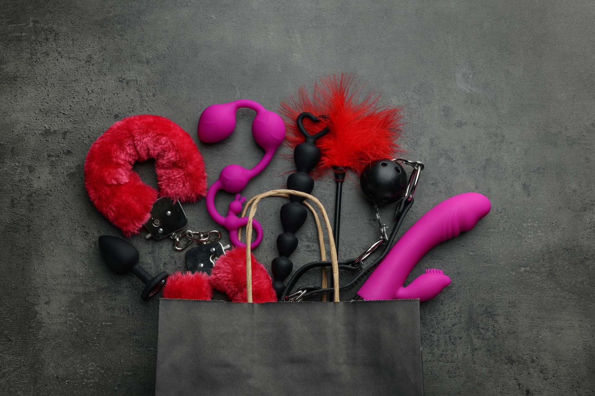 a collection of sex toys coming out of a bag over a black background