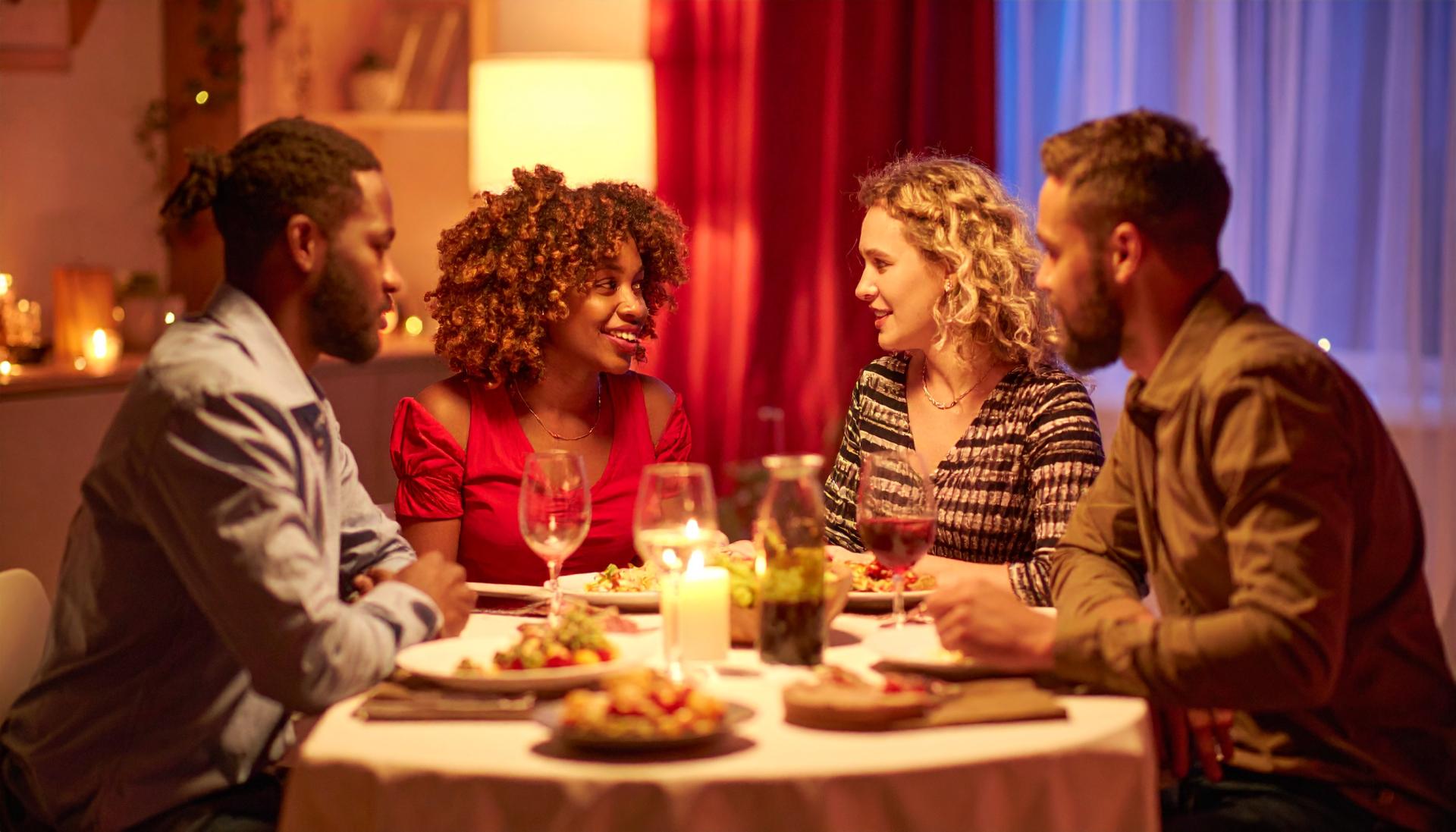 Four people having a conversation over dinner in dim red lighting Four people having a conversation over dinner in dim red lighting