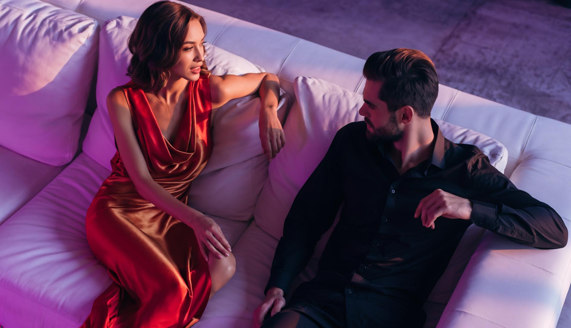 couple chatting on a white leather sofa at a night club