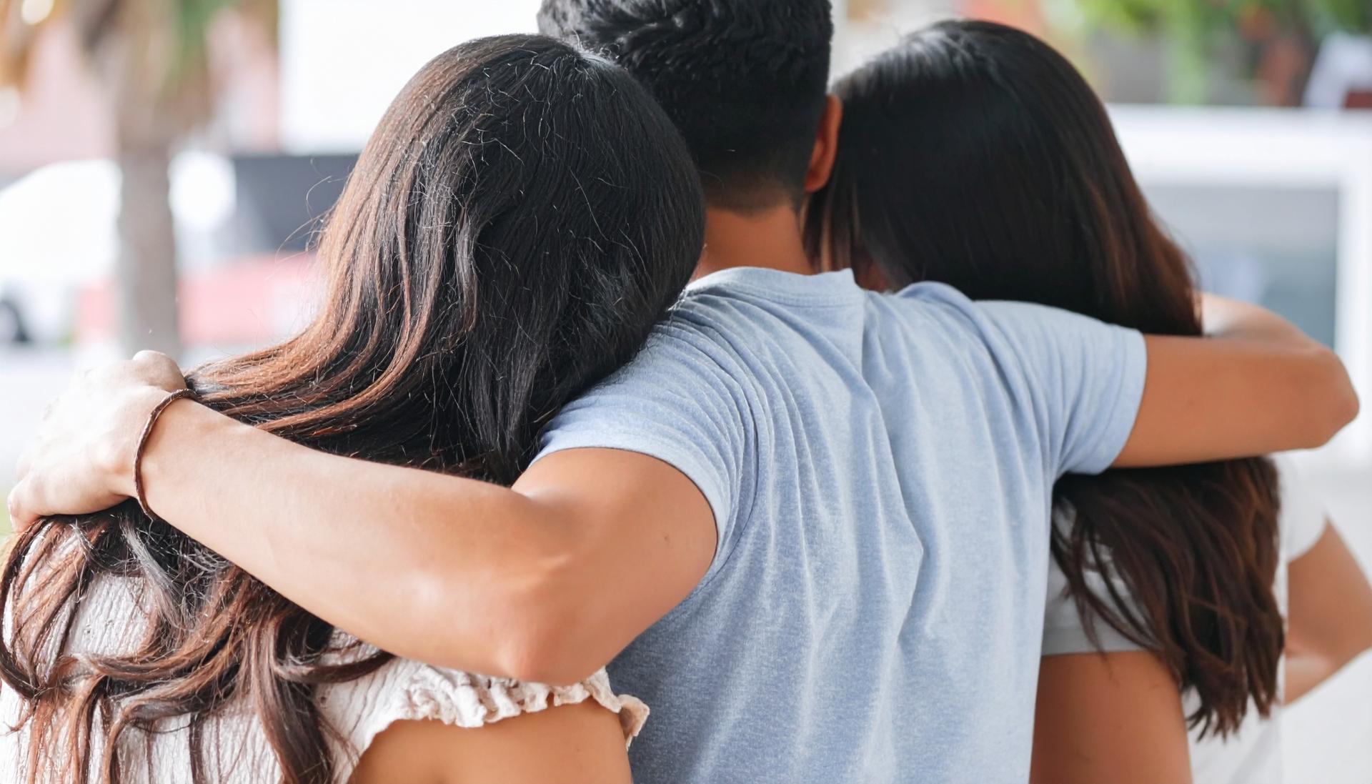 man with his arms over the shoulders of two brunette women