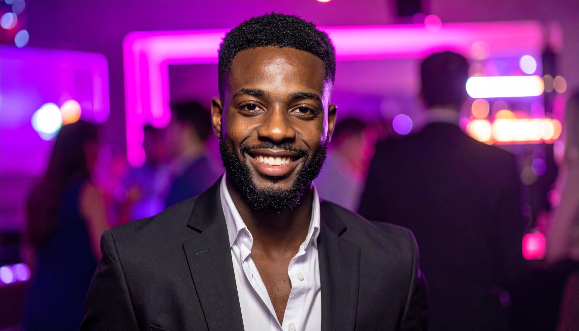 black man in a suit jacket at a night club with purple lighting
