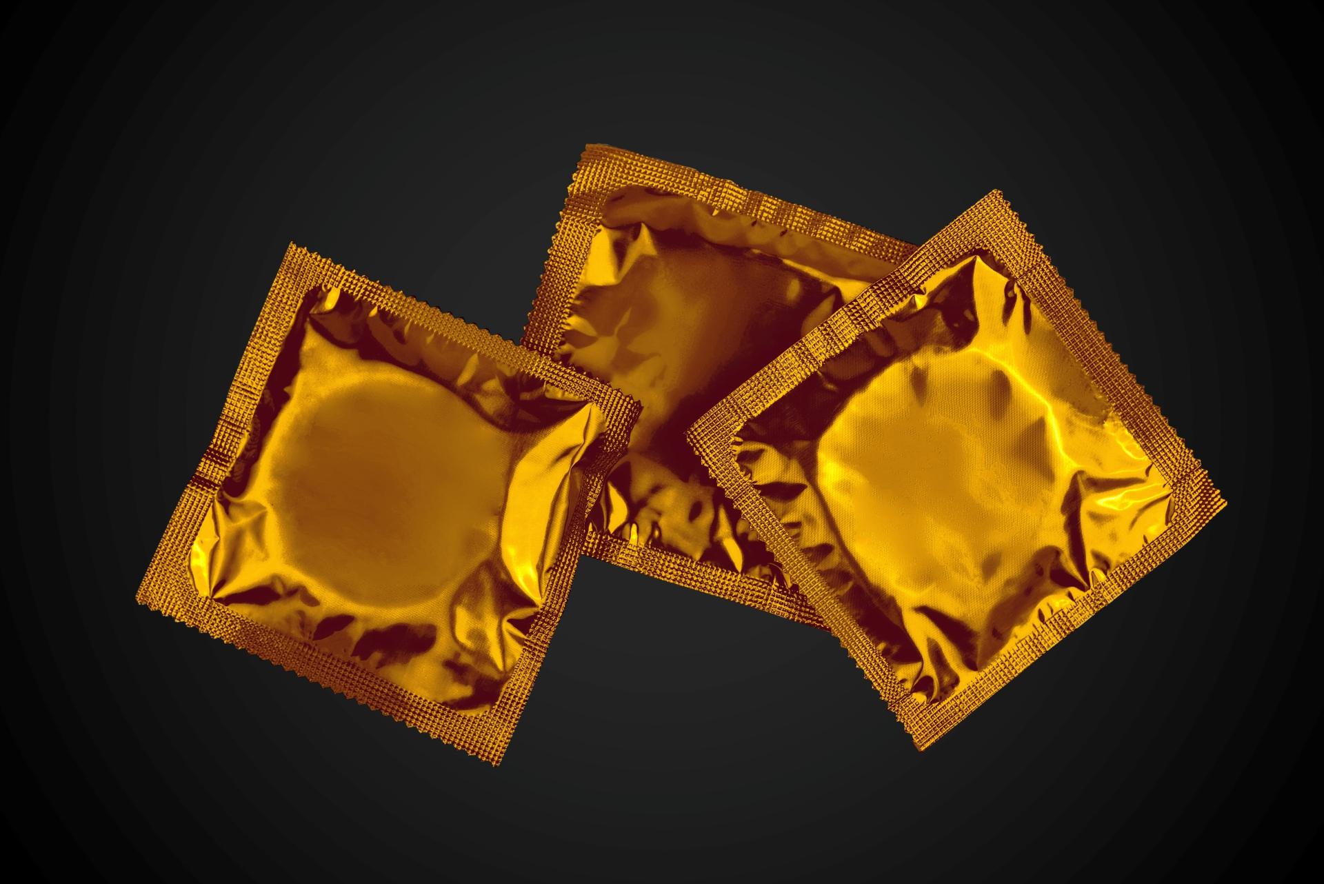 Gold condoms over a black background
