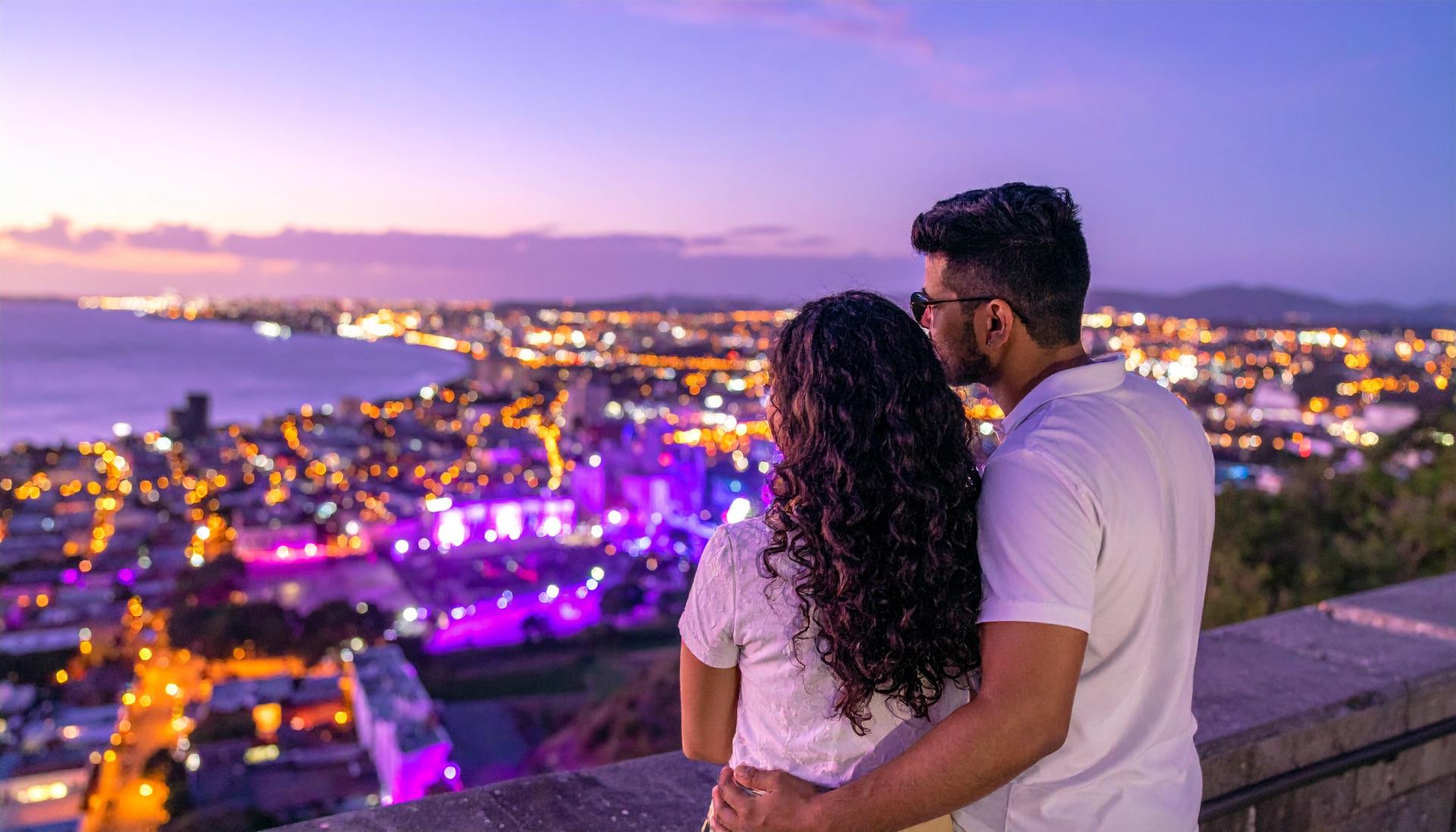couple overlooking an outdoor party with purple lighting