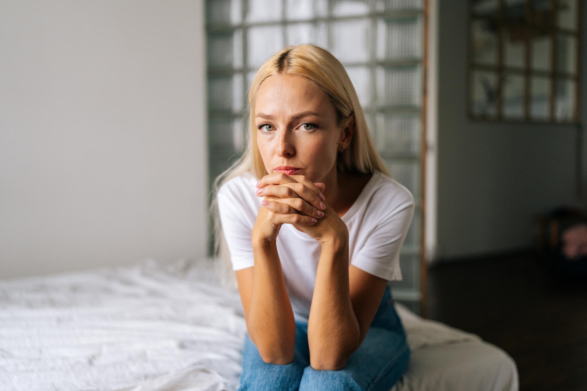 sad blonde woman sitting on a bed
