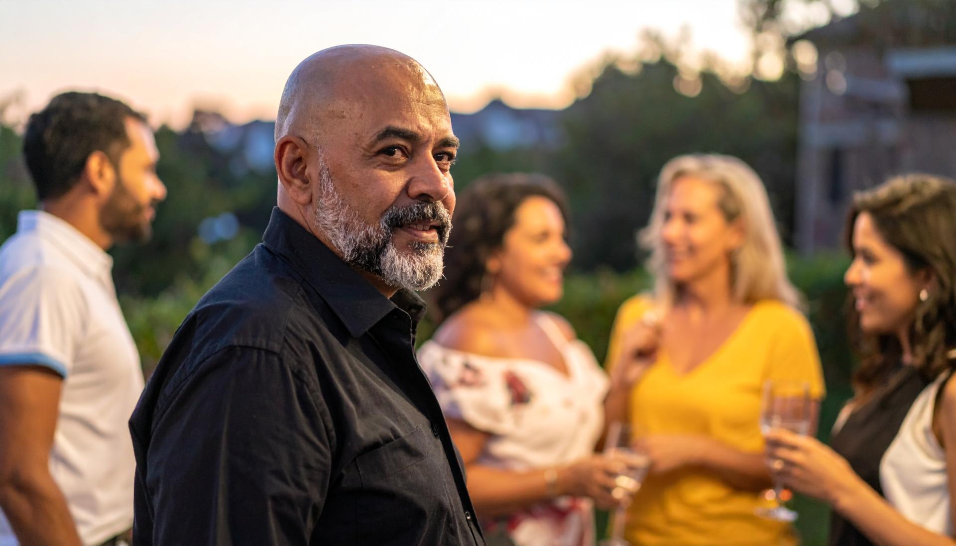 man with a grey beard in a black button-down shirt at a party