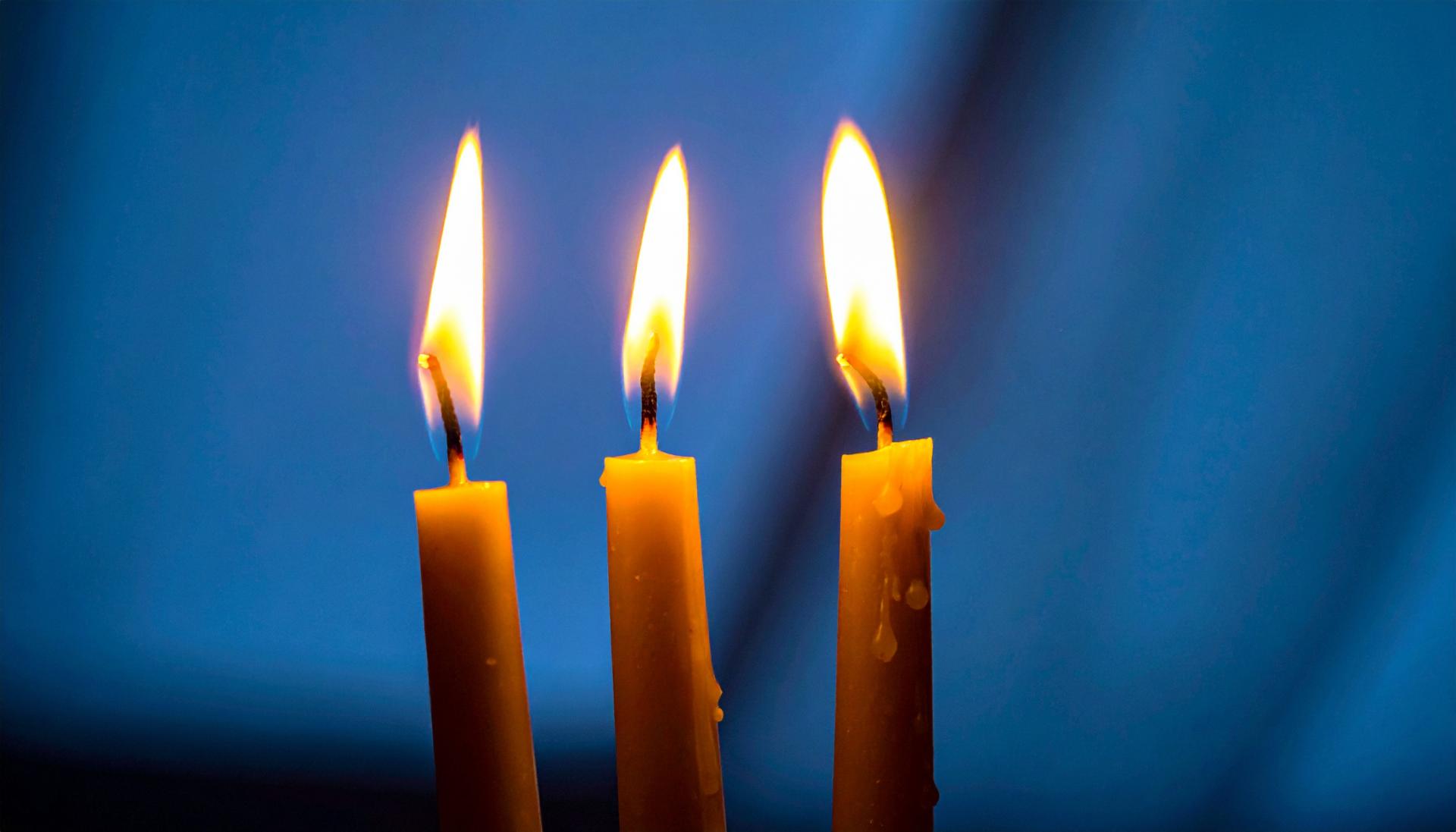 three candles in front of a dark background