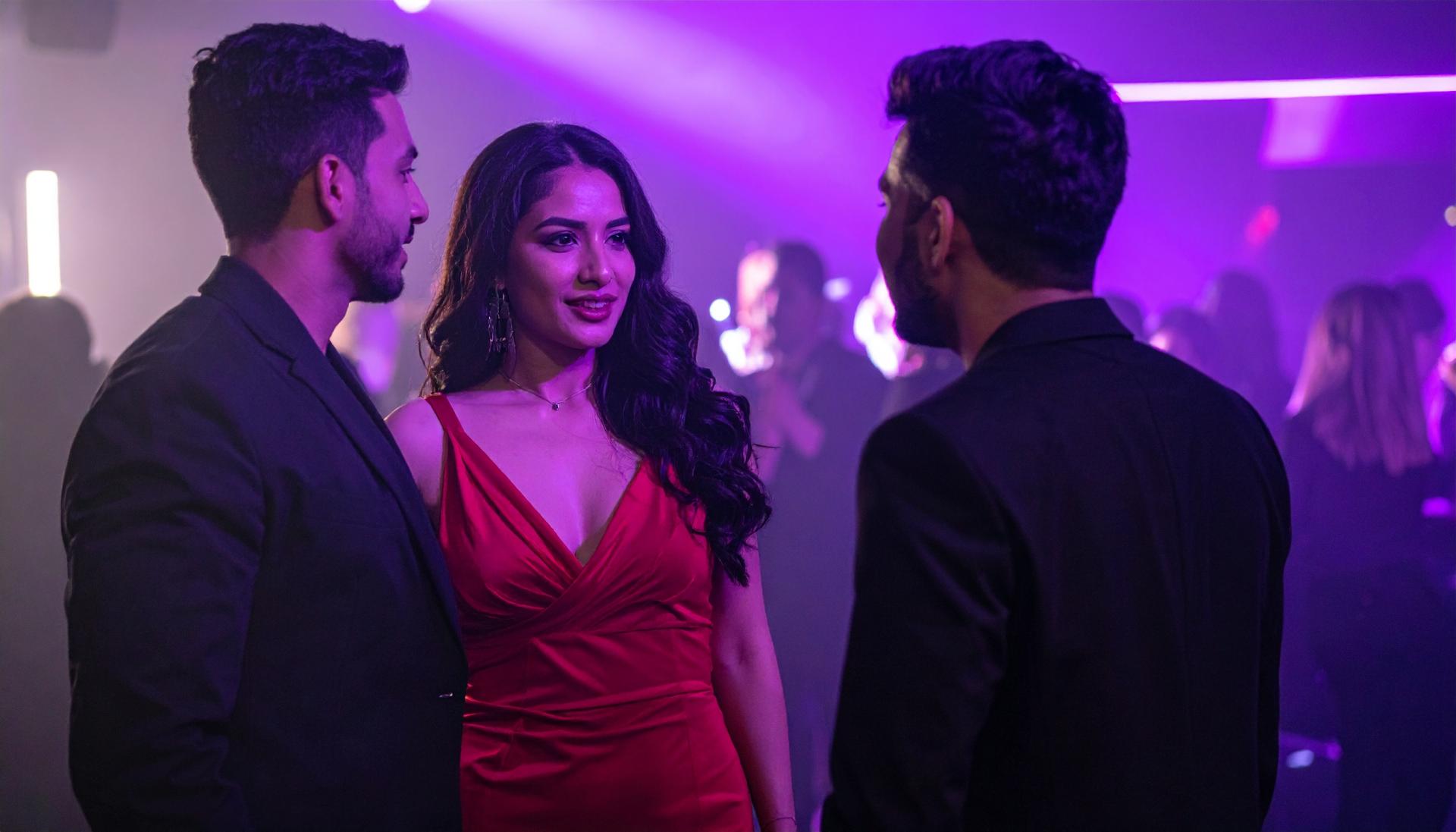 couple talking with a man at a nightclub with purple lighting