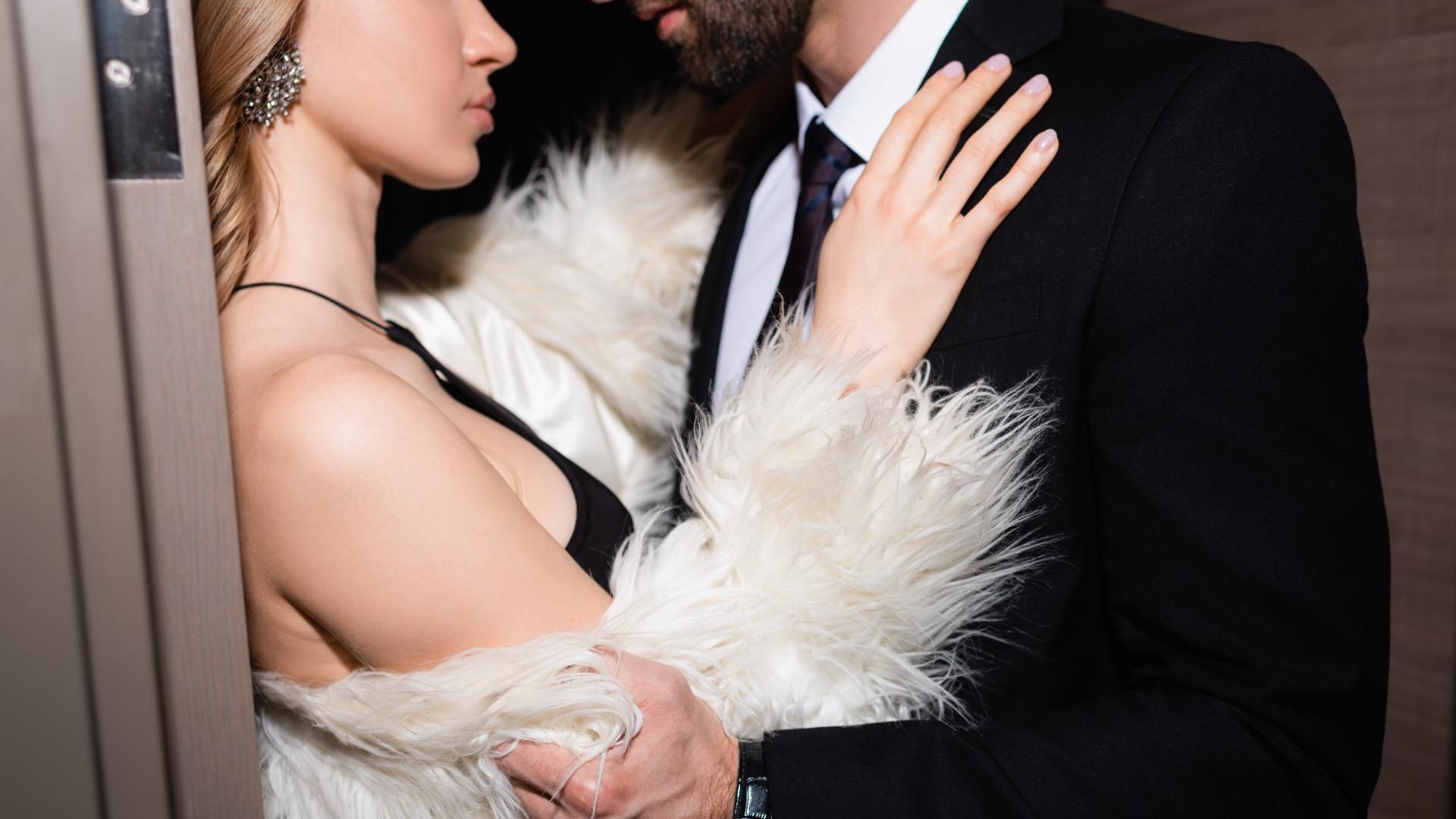 cropped view of a passionate couple in formalwear embracing in a doorway