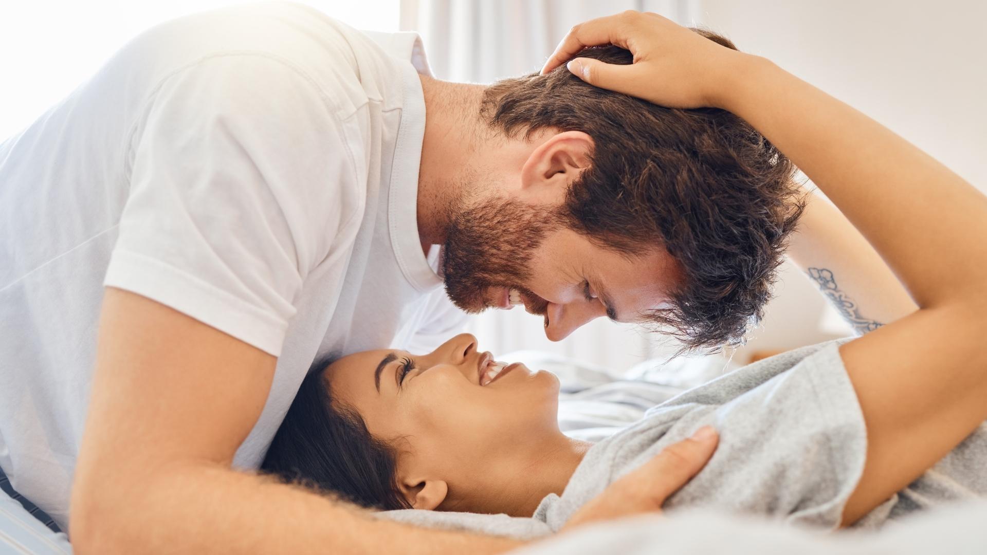 smiling couple in an intimate moment embracing on a bed