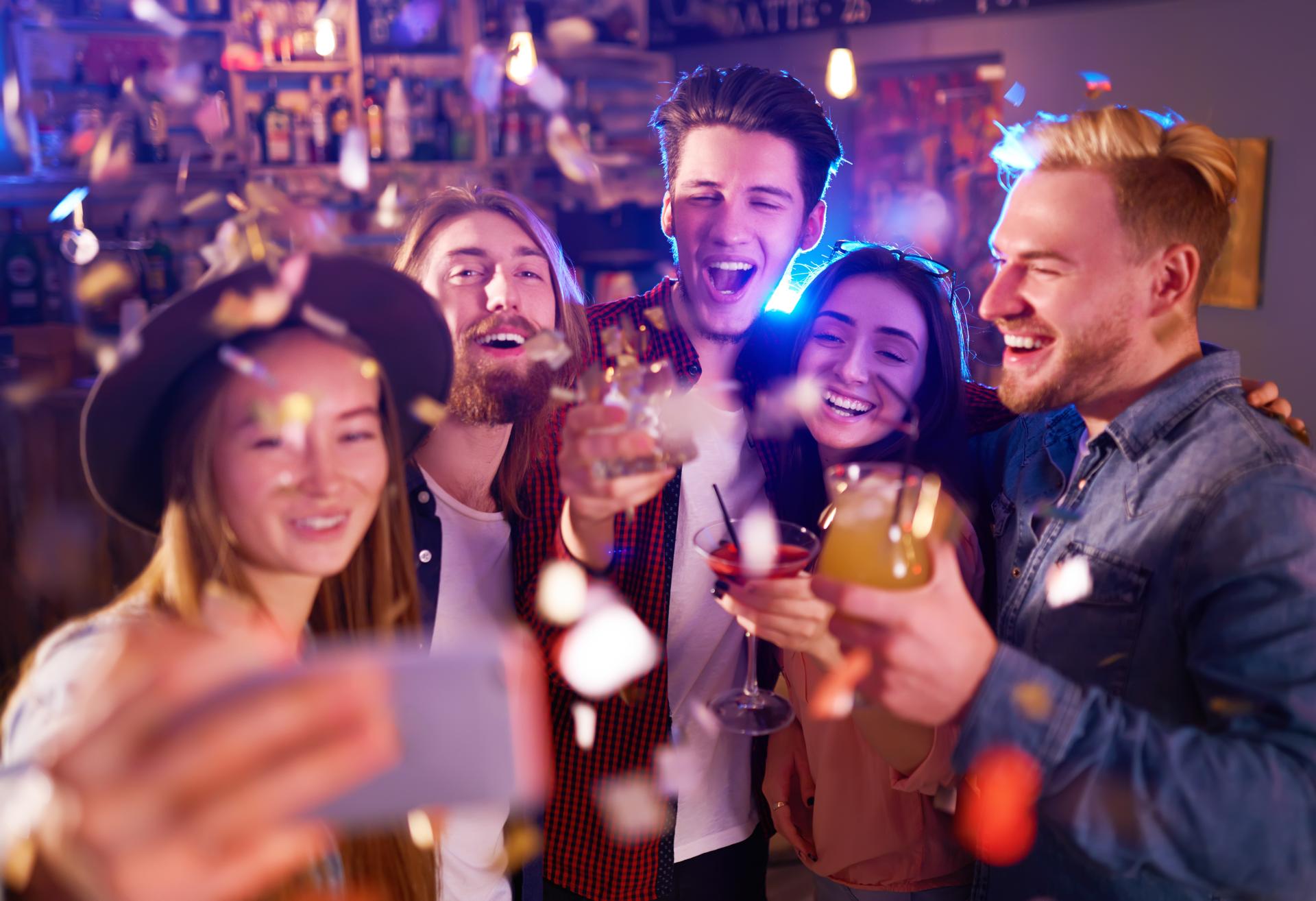 a group of men and women taking a selfie and having drinks at a club