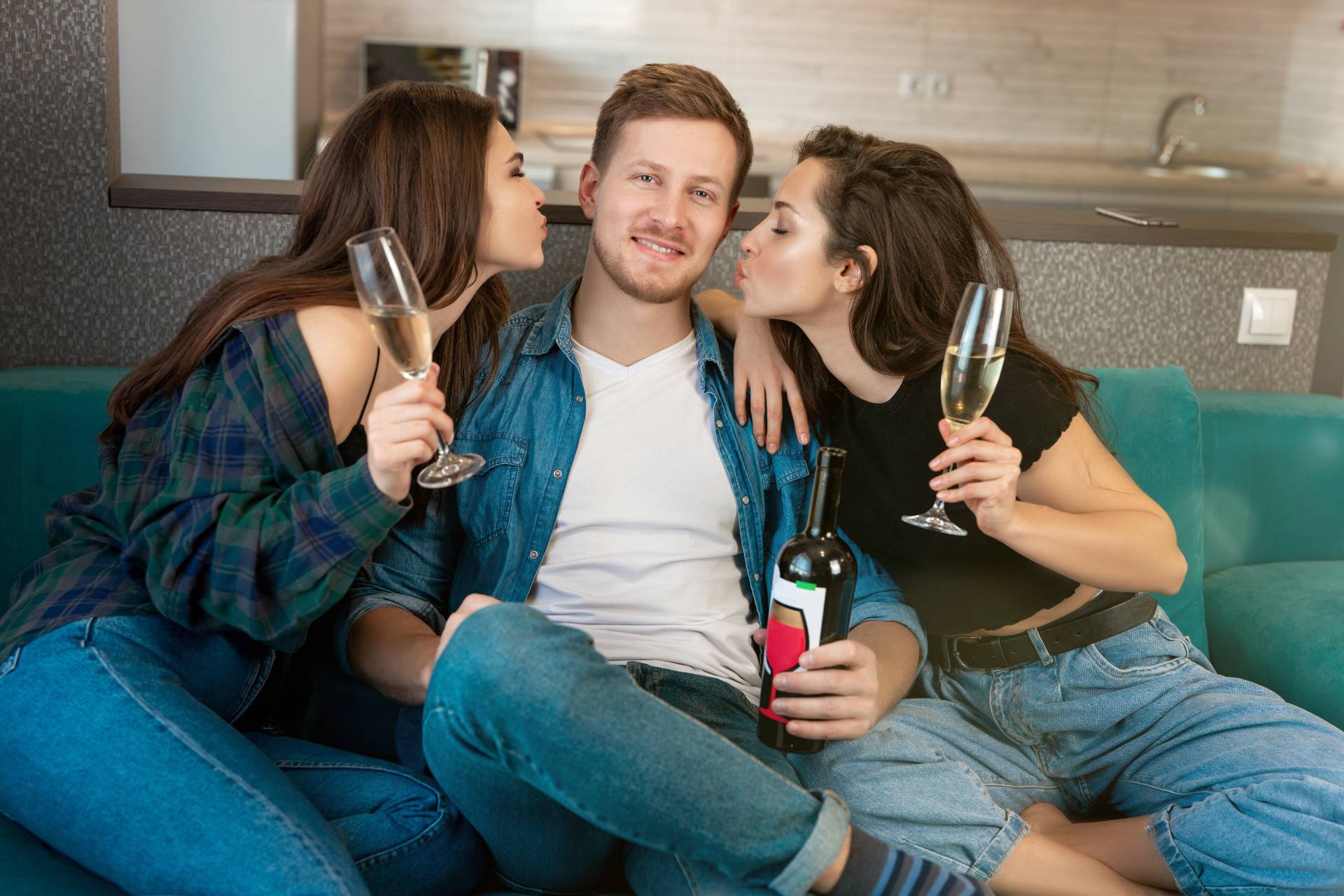 two women leaning in to kiss a man on each cheek while holding drinks