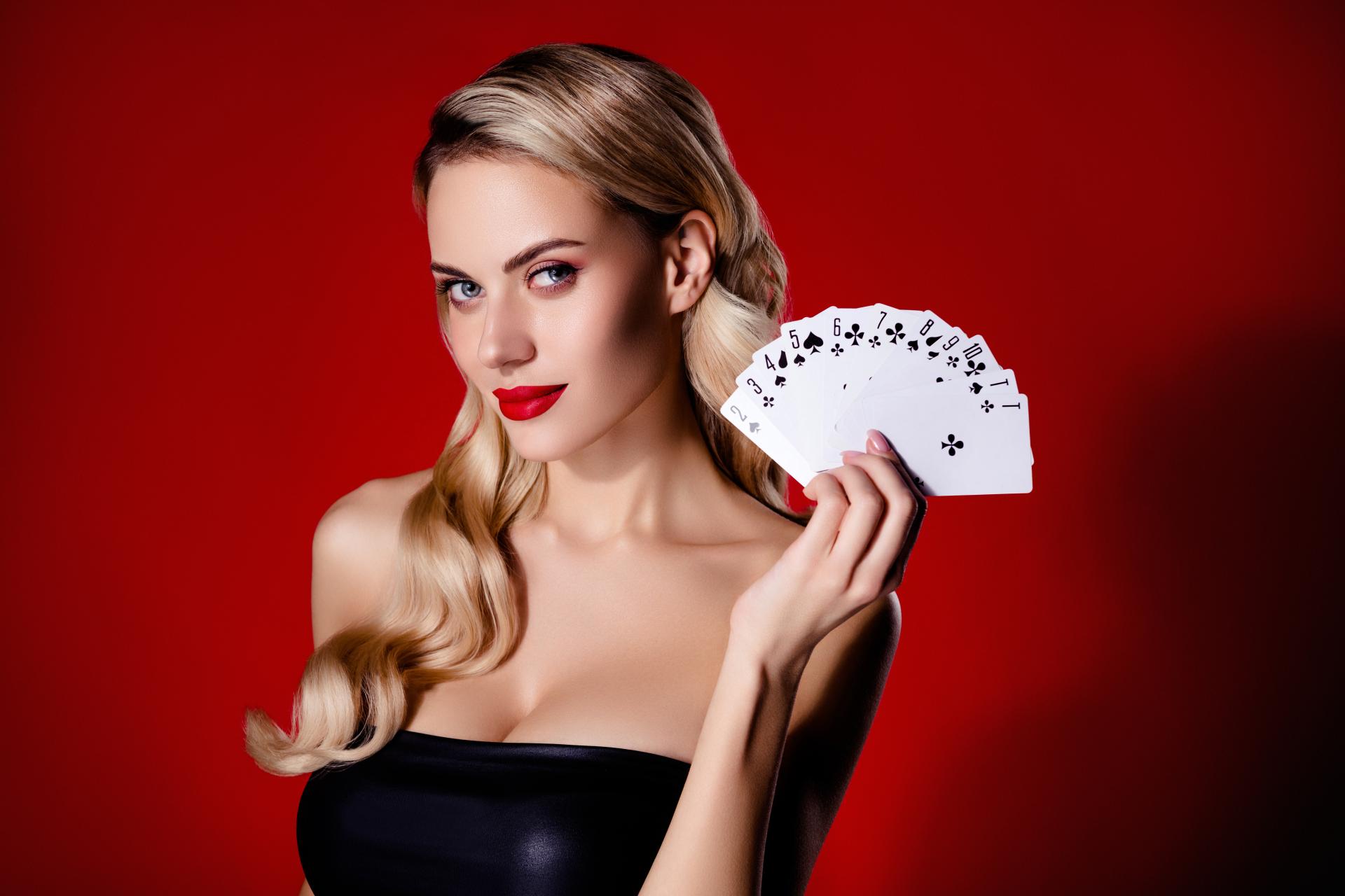 an attractive woman dressed in black holding playing cards