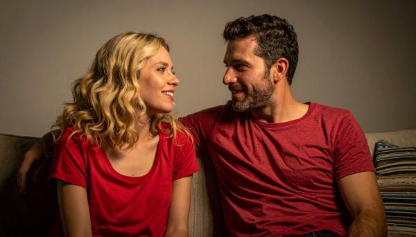 Couple wearing red having a conversation on a couch in dim lighting Couple wearing red having a conversation on a couch in dim lighting
