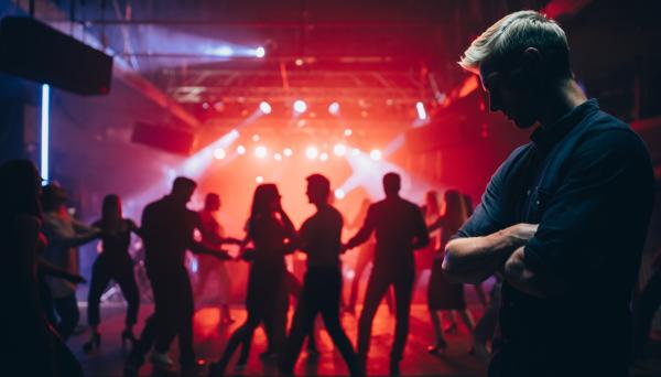 upset blond man in front of a group of people on the dancefloor