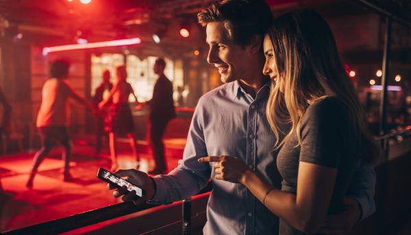 Smiling couple with a smartphone looking toward a night club dancefloor 483159