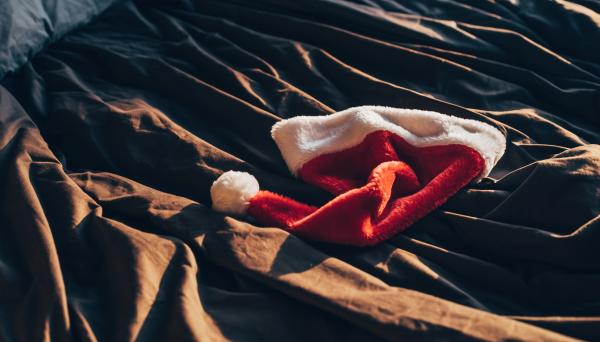 Santa hat on a bed with silky black sheets