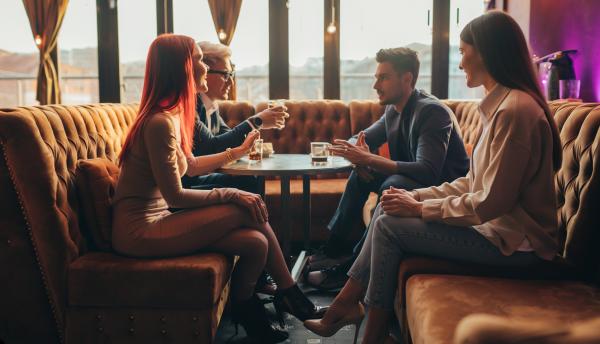 two couples having a lively conversation in a cocktail lounge