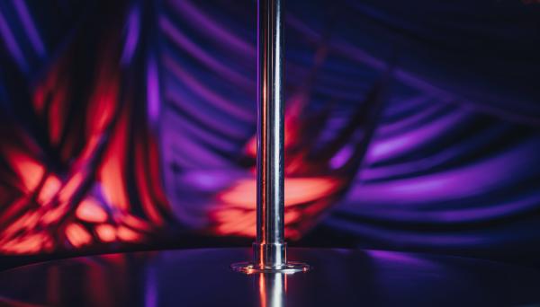night club dance pole with purple and red lighting in the background